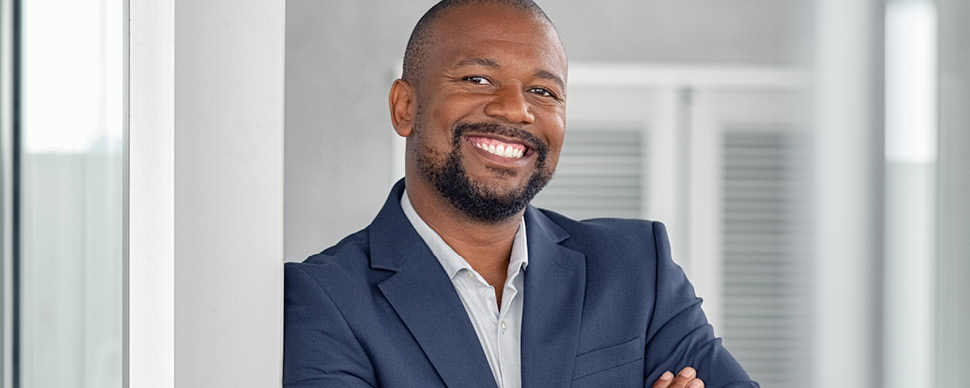 Person smiling in a suit, leaning against a pillar.