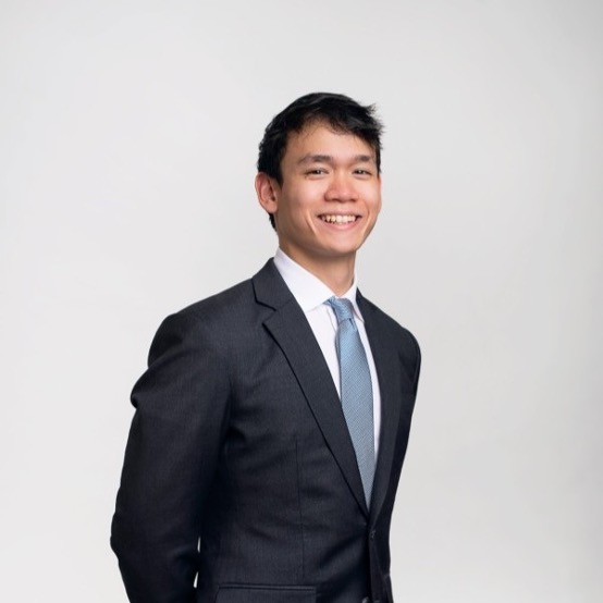 Person in a dark suit and blue tie smiling at the camera.