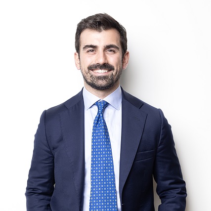 Person in a dark suit smiling against a white background.