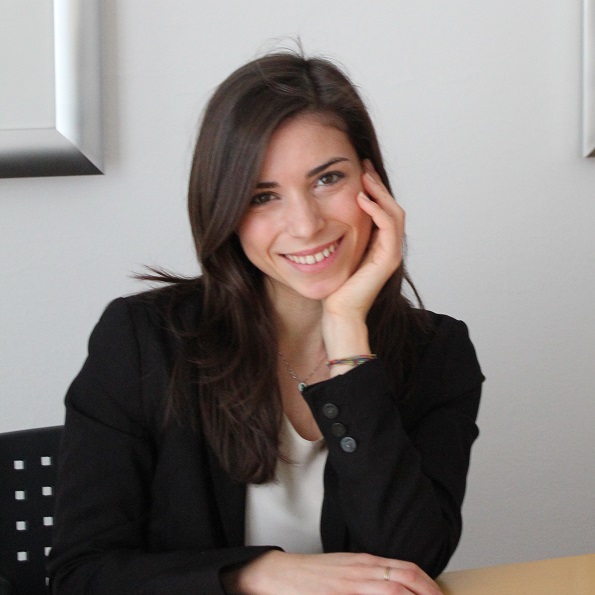 Person smiling at desk, hand on face.