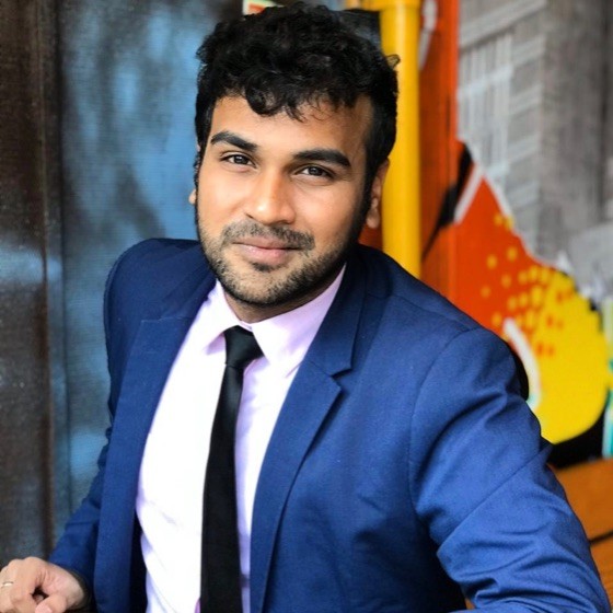 Person smiling in a blue suit, colorful background.