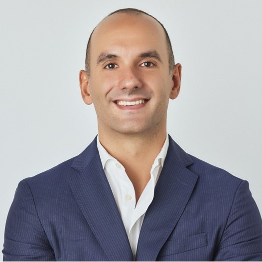 Person smiling in a blue suit with a white shirt.