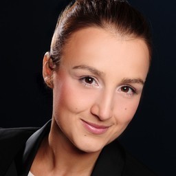 Person smiling in a professional headshot with dark background.