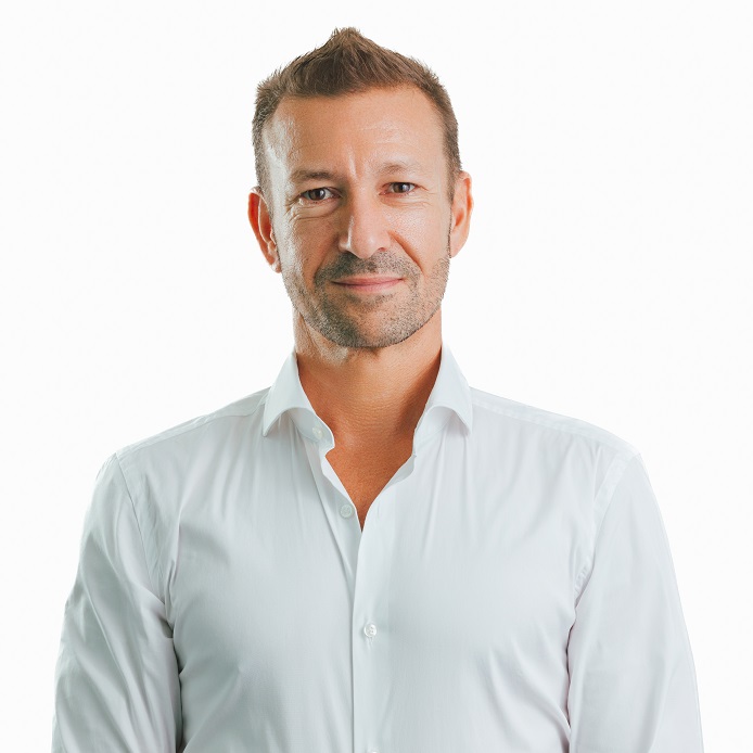 Person in a white shirt smiling against a plain background.