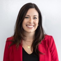 Person smiling against a plain background, wearing a red blazer.