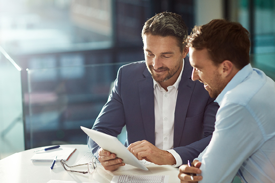 Two people in an office discussing documents at a table.