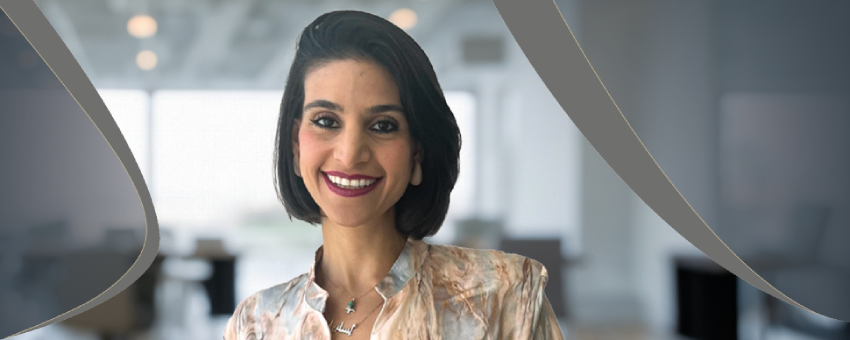 Person in patterned blouse standing in a modern office setting with curved graphic elements.