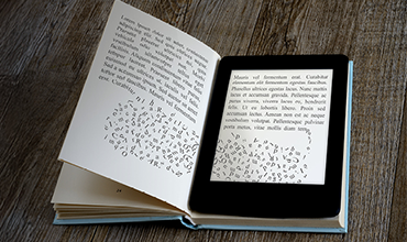 Open book with an e-reader displaying text placed on top.