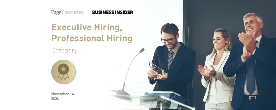 People standing on a stage during an award presentation, with one person holding a trophy while others applaud.
