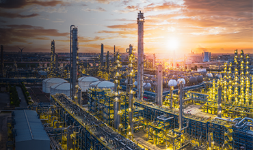 Industrial plant at sunset with illuminated structures and towers.