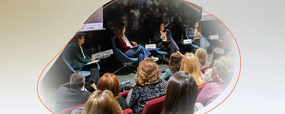 Panel discussion with several people seated on stage, speaking to an audience in a conference room.
