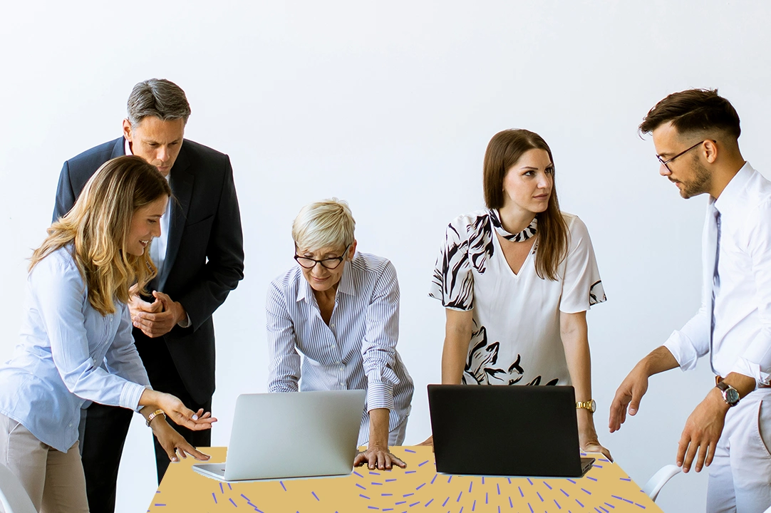 Group of colleagues gathered around a table, collaborating with laptops during a meeting.