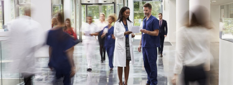 Healthcare professionals reviewing documents in a busy hospital corridor.