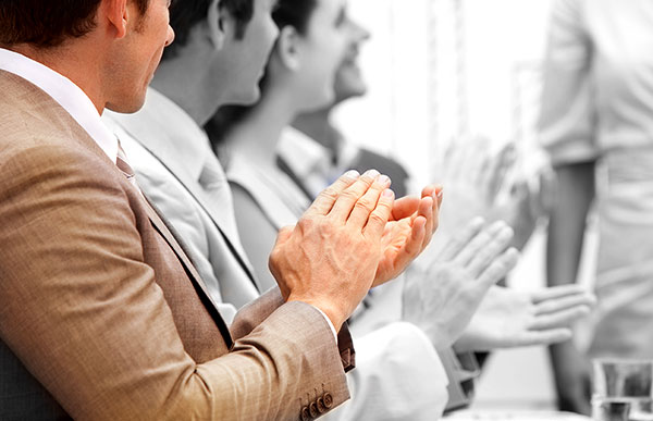 People sitting at a table, applauding.