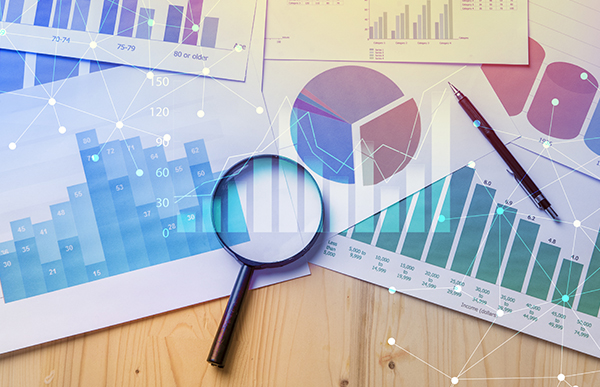 Magnifying glass on business charts and graphs on a desk.
