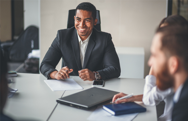 Person in a suit smiling during a meeting at a conference table.