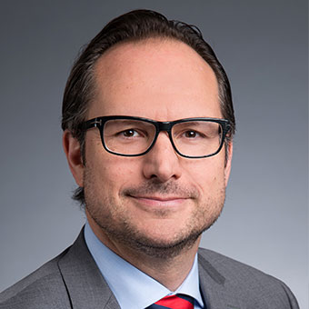 Person in glasses wearing a suit, smiling.