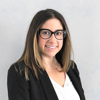 Person wearing glasses with shoulder-length hair and a blazer.