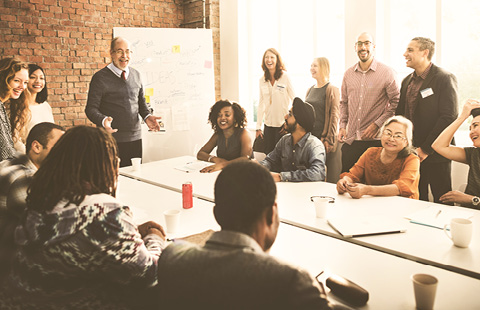 A diverse team having a discussion around a whiteboard in a bright meeting room.