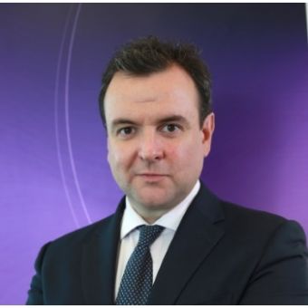 Person in a suit with a purple background.
