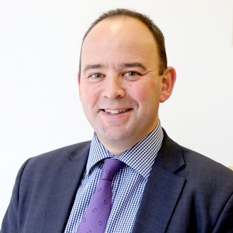 Person smiling in a suit with a white background.
