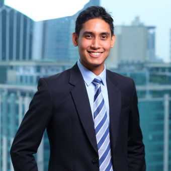 Person in a suit smiling with cityscape in the background.