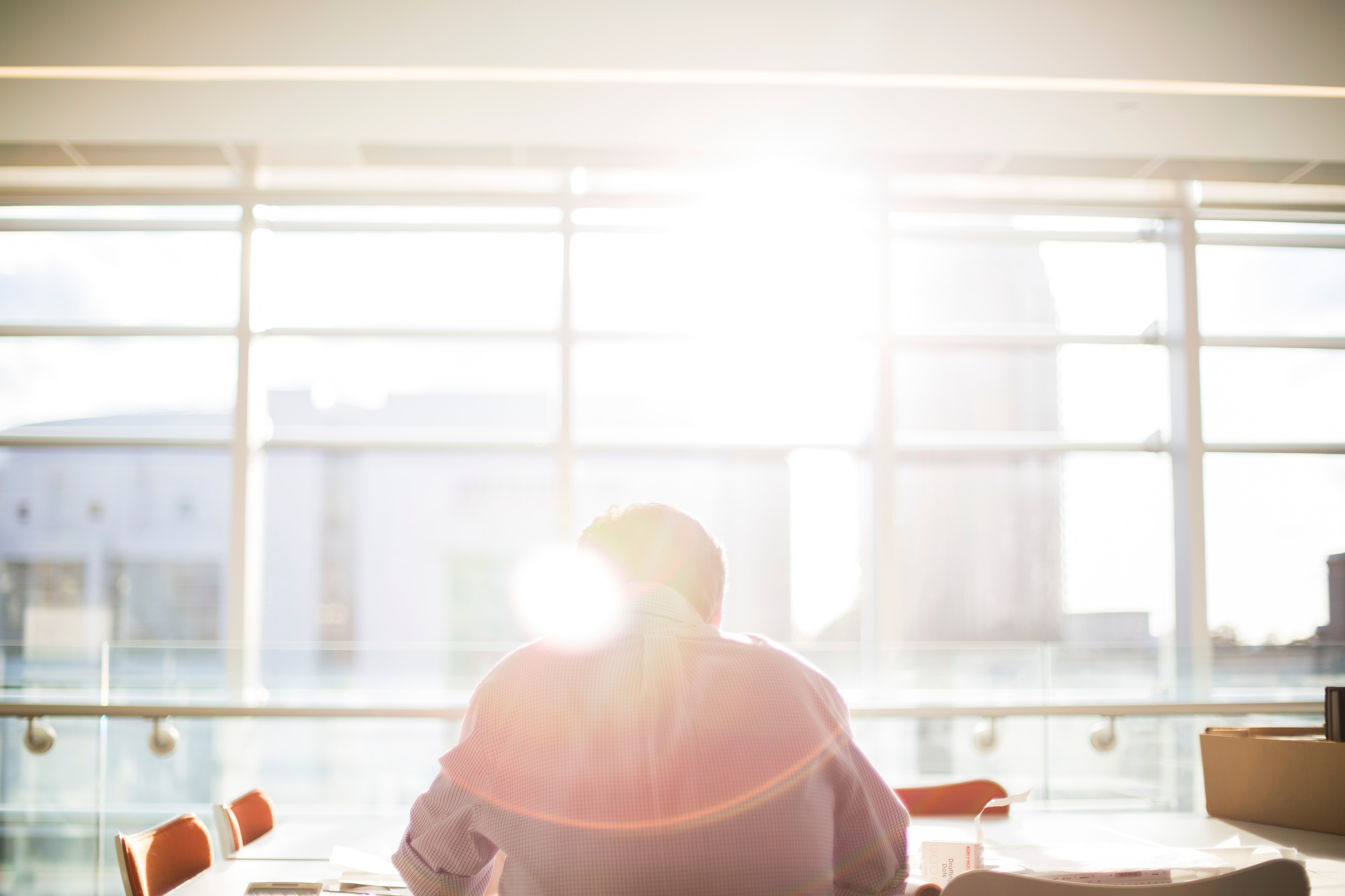 Person sitting at a table with sunlight streaming through a large window.