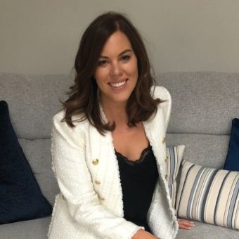 Person smiling while seated on a couch with striped pillows