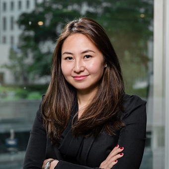 Person smiling in an office setting with arms crossed.