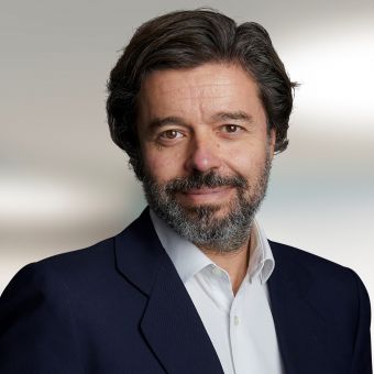 Person with a beard wearing a suit and white shirt, smiling at the camera.