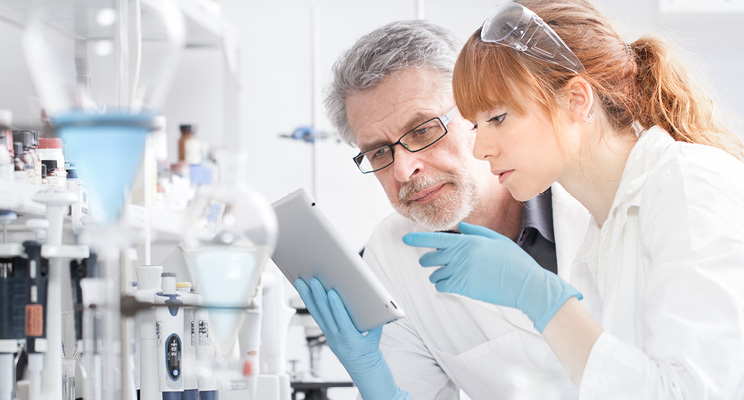 Researchers in a lab examining a tablet.