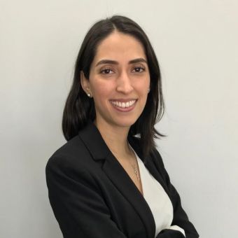 Person smiling in a professional outfit against a plain background.