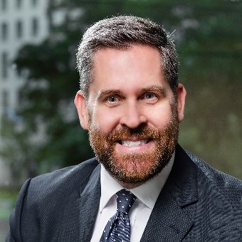 Person in a suit and tie smiling at the camera.