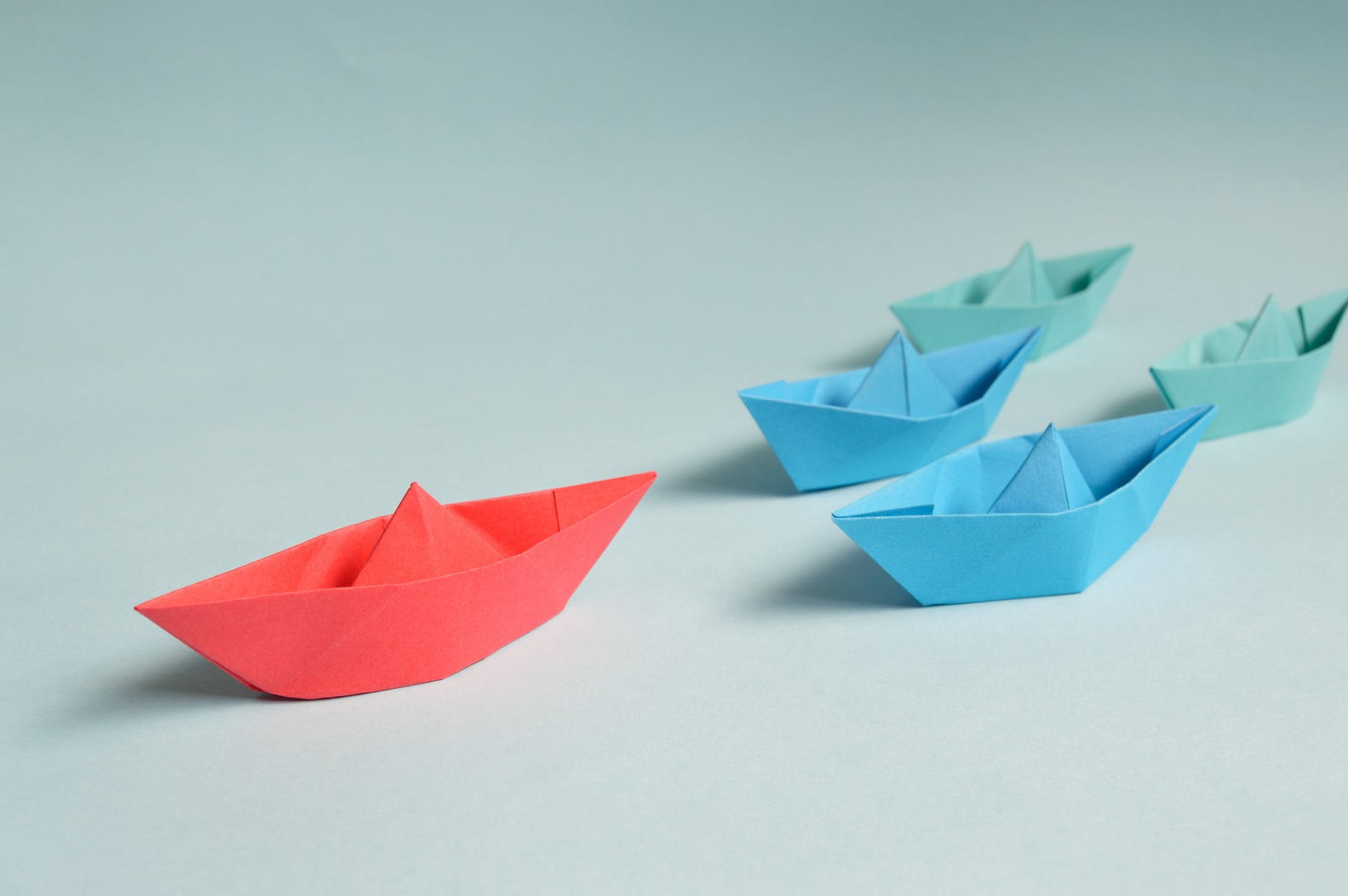 Colorful paper boats on a light blue background.
