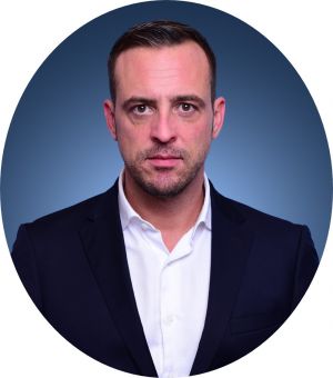 Portrait of a person in a suit against a blue background.