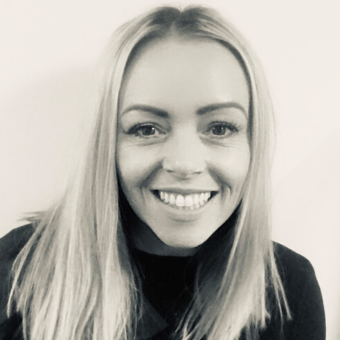 Black and white photo of a person smiling at the camera.