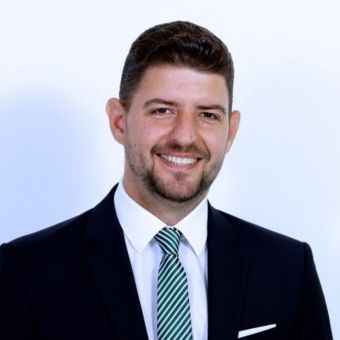 Smiling person in a suit and tie with a white background.
