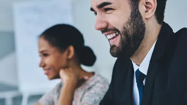 Two people smiling during a business meeting.