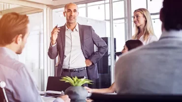 A person giving a presentation to coworkers in a modern office setting.