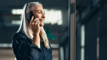 Person smiling while talking on a phone indoors.
