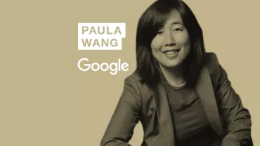 Person smiling in front of a beige background with Google logo.