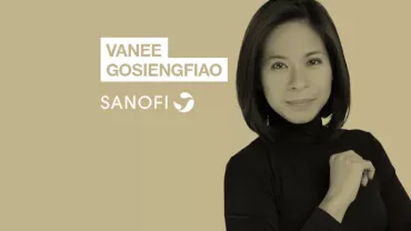 Person in black shirt with text 'Vanee Gosiengfiao' and 'Sanofi' on beige background.
