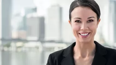 Smiling person in a suit with an urban skyline in the background.