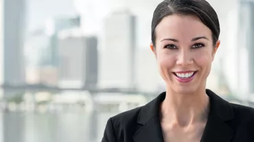 Smiling person in a suit with an urban skyline in the background.