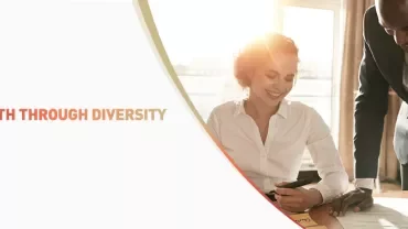 Two colleagues collaborating at a desk with the text 'Strength Through Diversity' displayed.