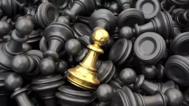 A golden pawn among many black chess pawns, symbolizing uniqueness.