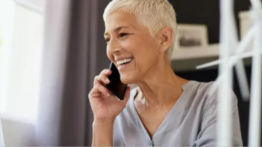 Person smiling and talking on the phone with a wind turbine model nearby.