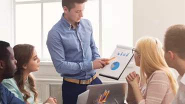 Team meeting with a presentation on charts and graphs displayed on a notepad.