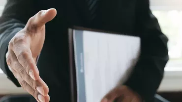 Person in a suit extends a hand for a handshake