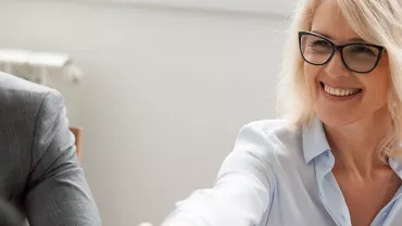 Person smiling and reaching out during a meeting.